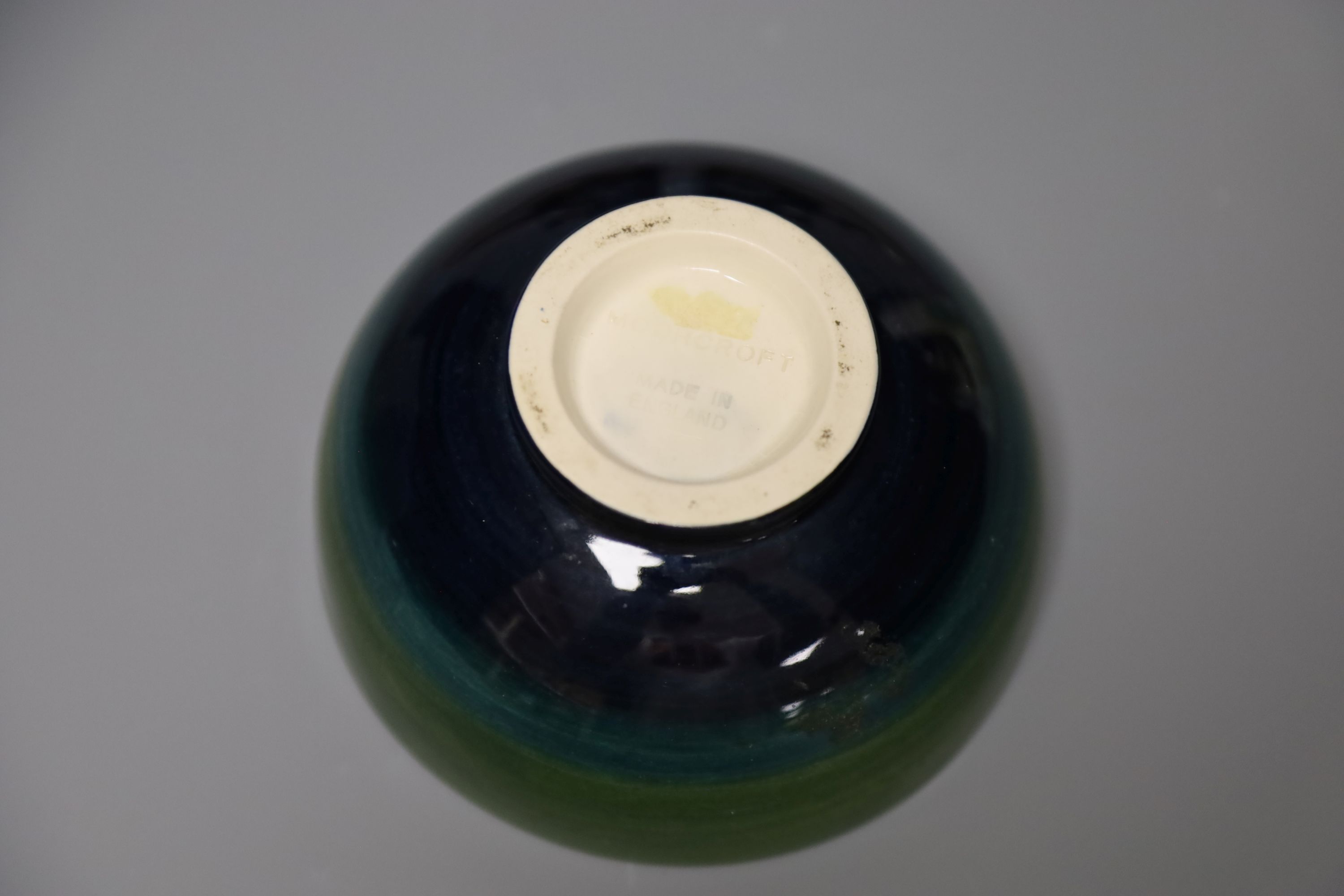 A Moorcroft green ground 'Columbine' pattern bowl, Dia 11cm and two pairs of ceramic bookends,